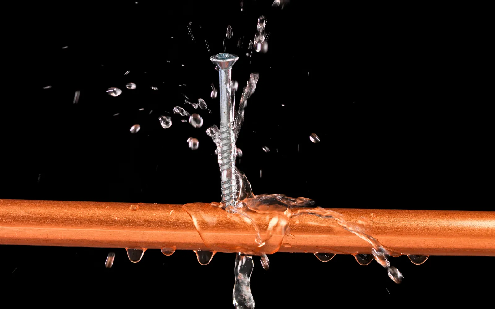 A screw going through a copper water pipe, representing burst pipe water damage in Lexington homes