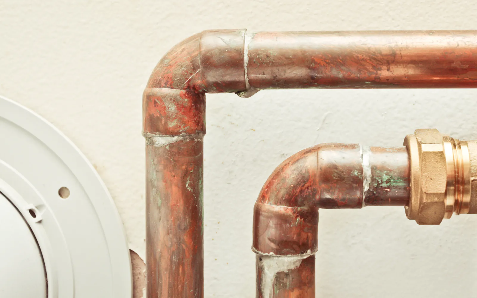 A dripping copper pipe, representing hidden leaks in homes that cause mold