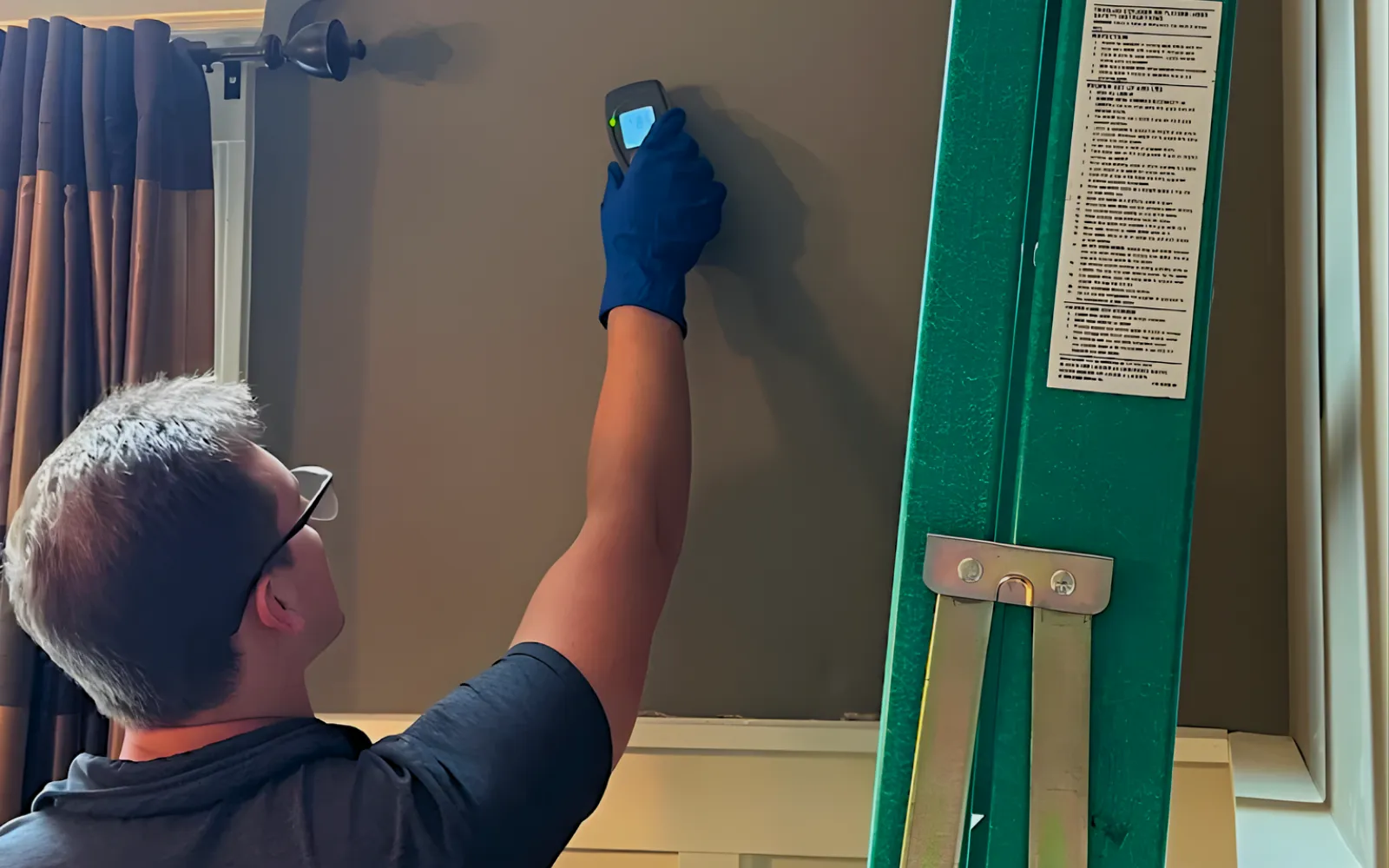Caleb, one of Spotless' team, performing a water damage inspection using a moisture meter to identify the extent of hidden water damage