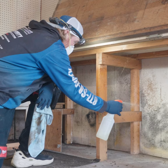One of Spotless' team cleaning mold from under a build in workbench