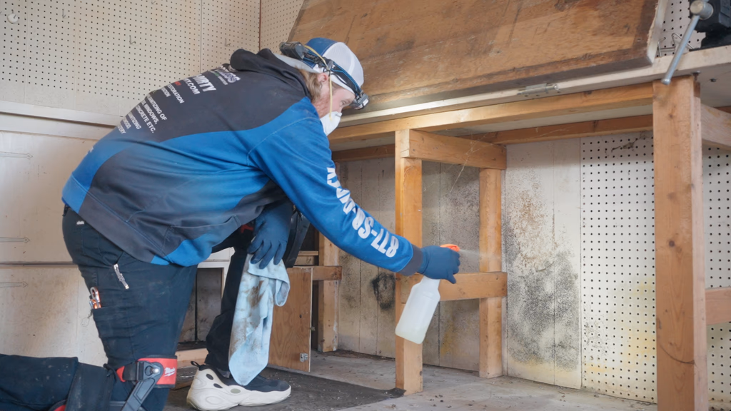 A member of Spotless' team spraying and removing mold under a Lexington home's garage workbench