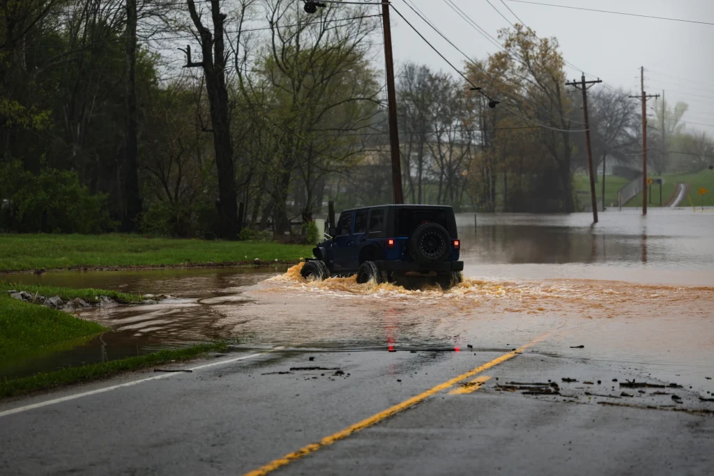 A car driving through flooded roads, representing water damage restoration in central KY