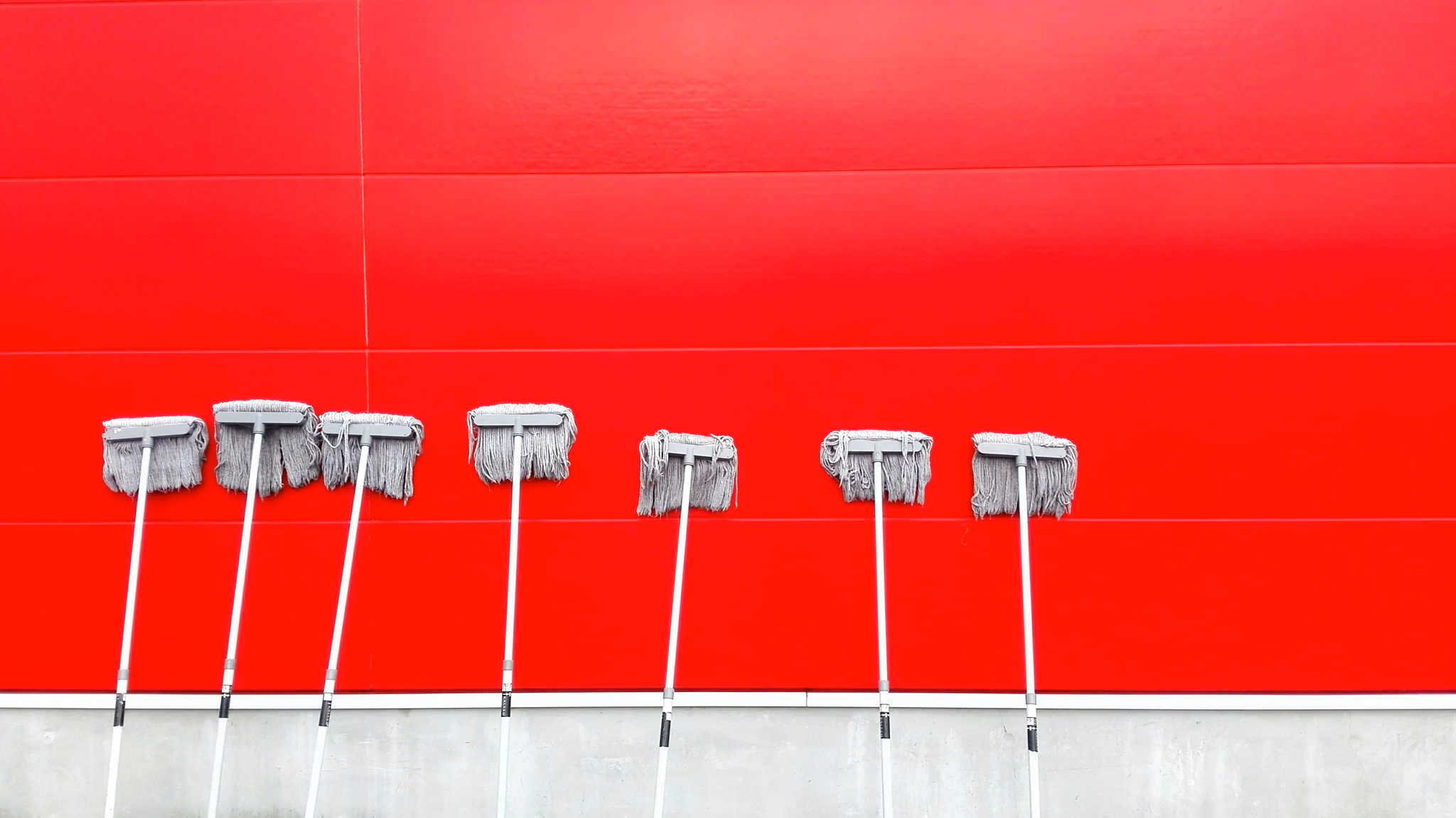 A series of mops resting against a wall