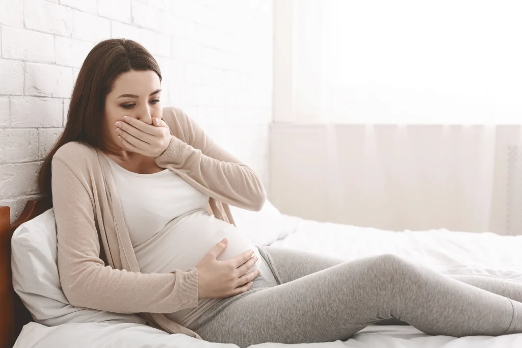 A pregnant lady coughing, representing the question "Can mold affect pregnancy?"