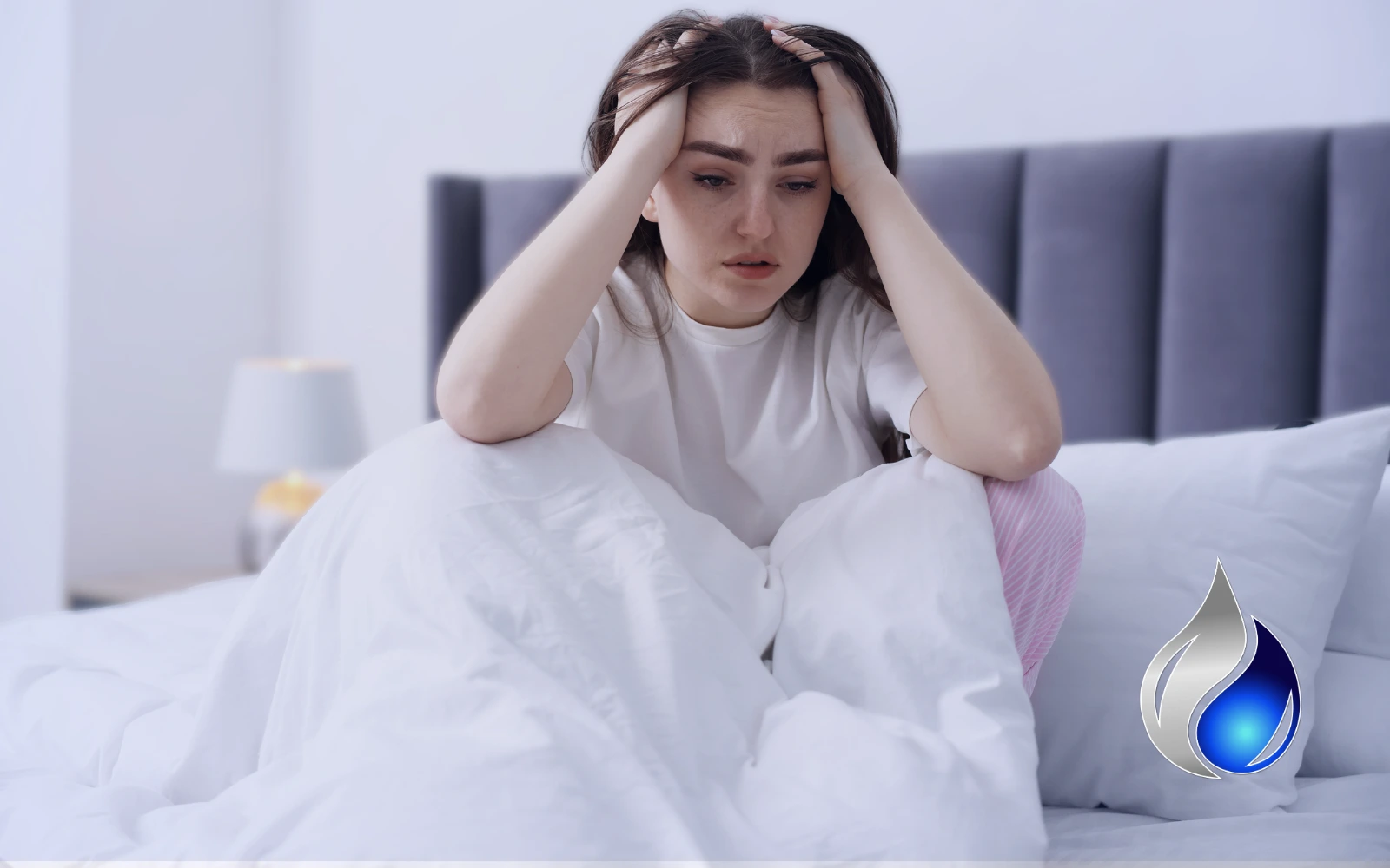 A woman sitting in bed with her head in her hands, representing chronic fatigue caused by mold toxicity
